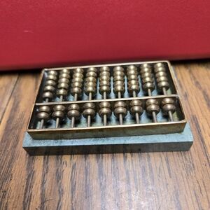 Small Brass Abacus Sitting On A Jade Base.